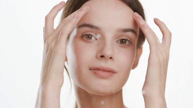 Young woman strokes forehead behind foggy glass with water drops