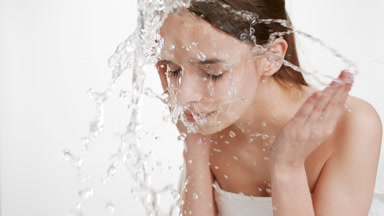 Attractive young slim woman wearing white towel hair washes face