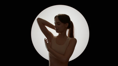 Pretty slim woman in beige top strokes her armpit smiling widely