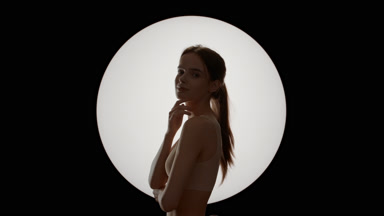 Cute woman with ponytail strokes jawline turning head to camera