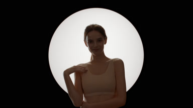 Gorgeous woman strokes shoulder, clavicles and looks at camera