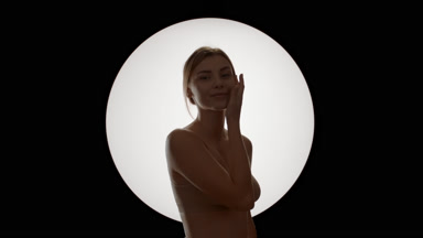 Attractive Caucasian woman in beige top strokes jawline turning