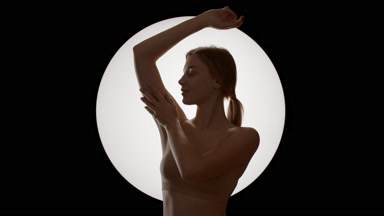 Young Caucasian woman in beige top strokes armpit looking aside