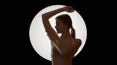 Young Caucasian woman in beige top strokes armpit turning head