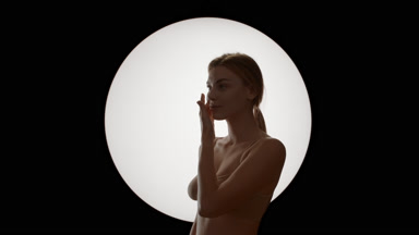 Caucasian woman in beige top strokes jawline turning to camera