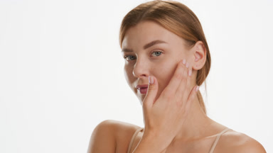 Young Caucasian woman strokes jawline turning head to the camera