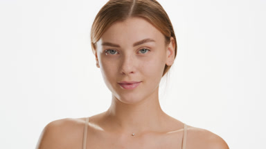 Beautiful young Caucasian woman strokes cheek looking at camera