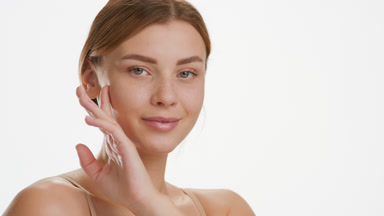 Cute young slim Caucasian woman strokes her jawline turning head