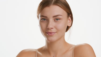 Attractive Caucasian woman touches face smiling wide for camera