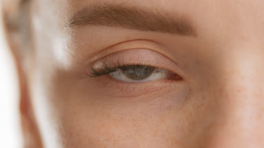 Caucasian female model opens her eye and looks at the camera