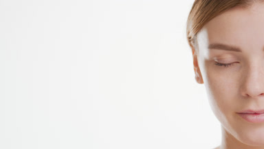 Young brown-haired woman opens her eye and looks at the camera