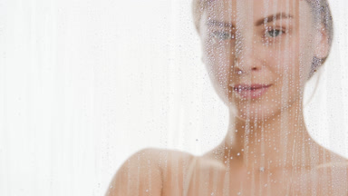 Attractive woman wipes fogged glass with hand and smiles wide