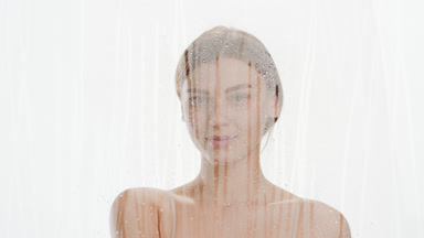 Young woman wipes fogged glass with hand and smiles for camera