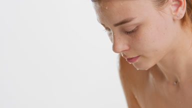 Good-looking young woman with long brown hair washes wet face