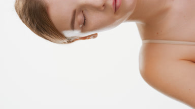 Slim young woman with brown hair opens eye and looks at camera