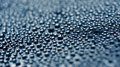 Water drops appear from shadow for a while on blue background