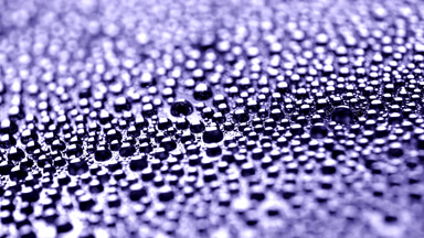 Water drops appear from shadow for a while on violet background