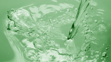Pouring water creating ripples and bubbles on green background