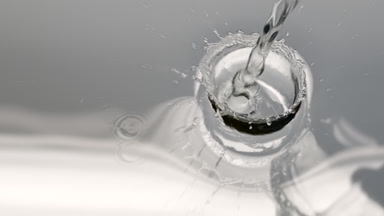 Water is poured creating ripples and bubbles on grey background