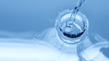 Water is poured creating ripples and bubbles on blue background