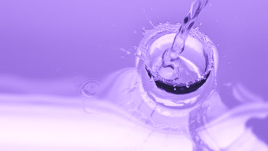 Water poured creating ripples and bubbles on violet background