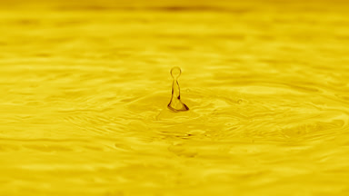 Drops fall on water surface creating rings on yellow background