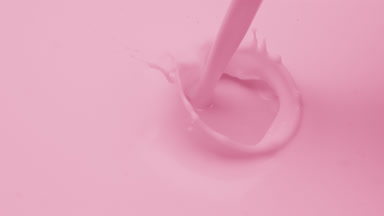 Macro of pink liquid is poured splashing on pink background