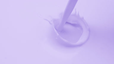 Macro of purple liquid is poured splashing on purple background