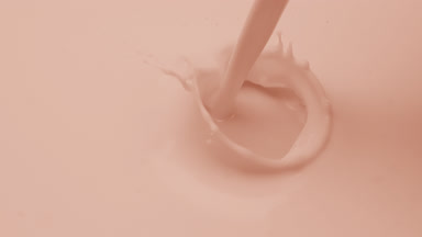 Macro of beige liquid is poured splashing on beige background