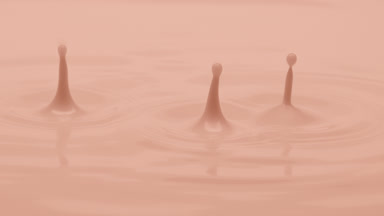 Macro jib shot of beige opaque liquid is dripped splashing
