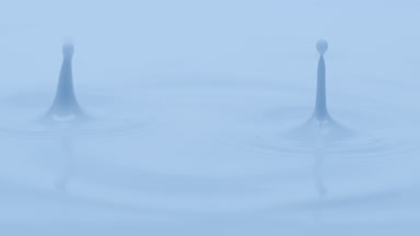 Blue liquid is dripped creating ripples on blue background