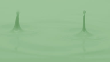 Green liquid is dripped creating ripples on green background