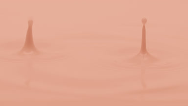 Beige liquid is dripped creating ripples on beige background