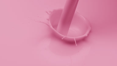 Pale pink liquid is poured creating bubbles on pink background