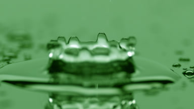 Small water drop drips on big one splashing on green background