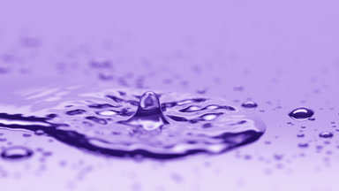 Small drop falls on big creating ripples on violet background