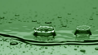 Two drops fall on big rippling one splashing on green background
