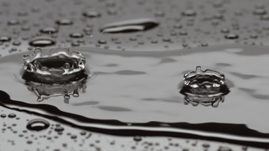 Drops drip on big rippling one splashing on grey background