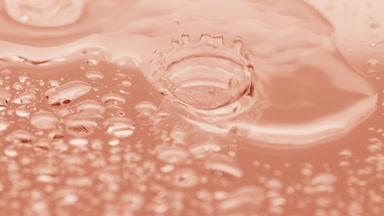 Water drops fall down on big one splashing on beige background