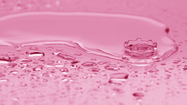 Two water drops drip on big one splashing on pink background