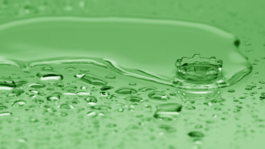 Two water drops drip on big one splashing on green background
