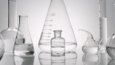 Close-up shot of lab glassware with water on grey background