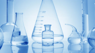 Close-up shot of lab glassware with water on blue background