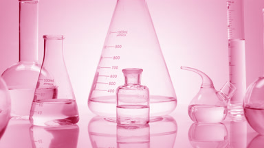 Close-up shot of lab glassware with water on pink background