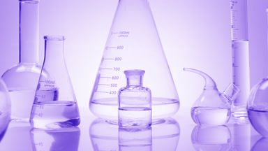 Close-up shot of lab glassware with water on violet background