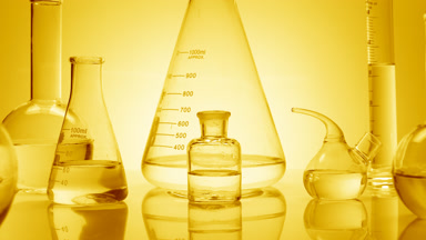 Close-up shot of lab glassware with water on yellow background