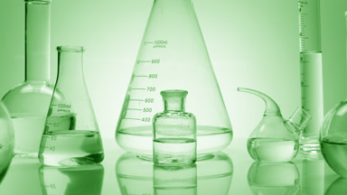 Close-up shot of lab glassware with water on green background