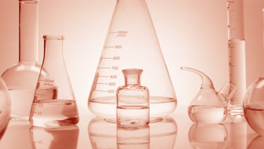 Close-up shot of lab glassware with water on beige background