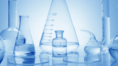 Drops drip in bottle surrounded by glassware on blue background