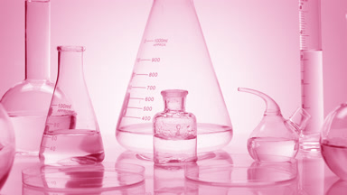 Drops drip in bottle surrounded by glassware on pink background